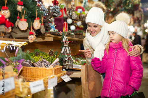 Joyous mother with little daughter buying decorations for Xmas at an open air market. High quality photo