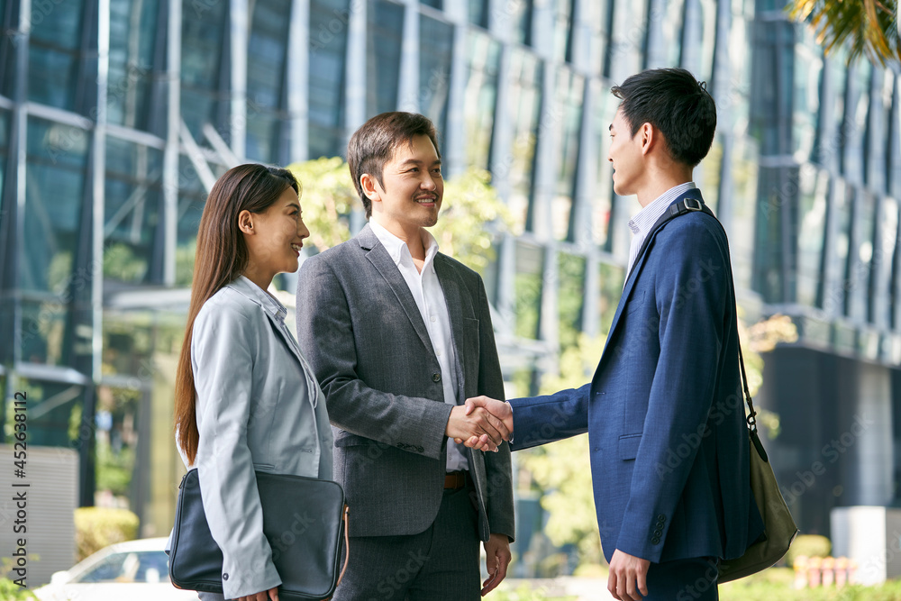 asian business associates shaking hands outdoors asian business associates shaking hands outdoors