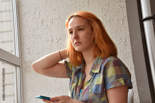 Faceless young woman with ginger hair browsing smartphone in bright room