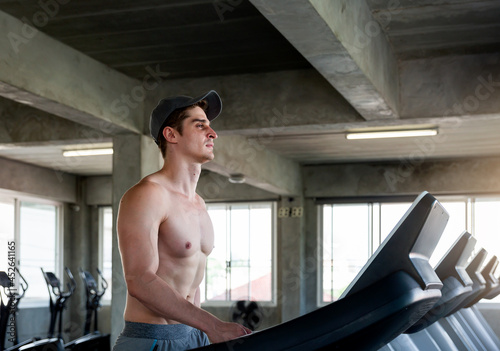 Handsome muscle young man running on treadmill at sport gym, Sportsman doing exercises, Sport fitness and muscles concept