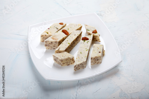 Halva with pistachios and almonds on a white porcelain plate on a white background. photo