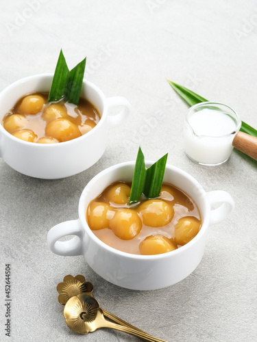 Bubur candil or kolak biji salak, Indonesian traditional food made from sticky rice flour, brown sugar and coconut milk. Popular during ramadan. Served in white bowl on grey background. Close up. 