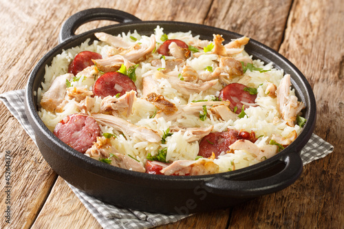 Fotografia Tasty Chicken bog one-pot meal is a combination of chicken, smoked sausage, and rice closeup in the pan on the table