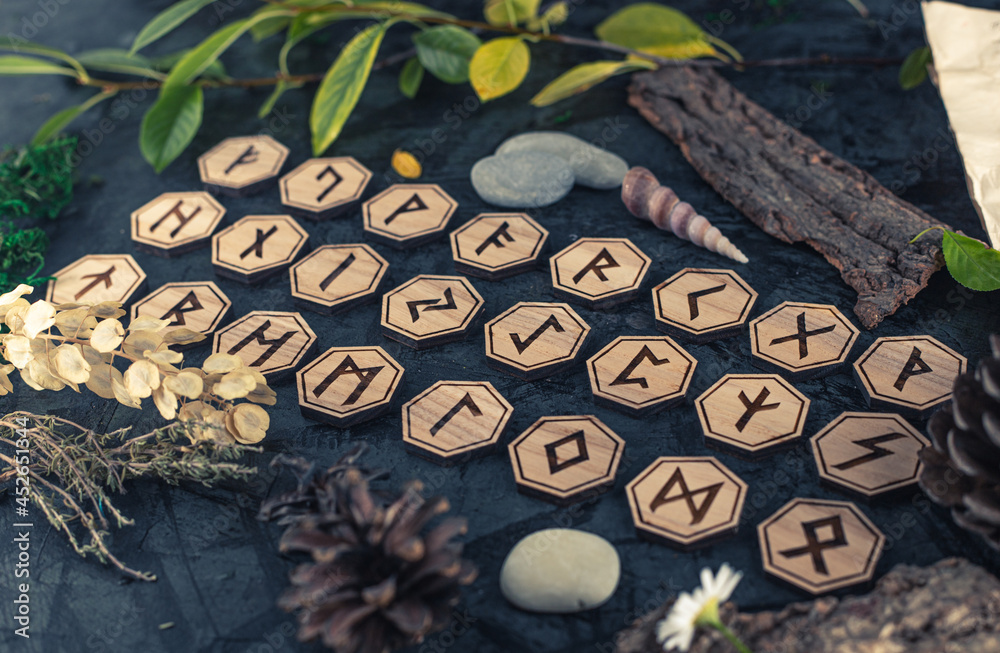 Wooden runes are lying on the table among various objects. Astrology and esotericism. Senior Futhark Wooden runes are lying on the table among various objects. Astrology and esotericism. Senior Futhark