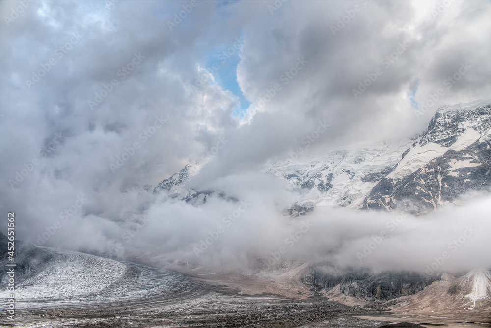 The main Caucasian ridge in the clouds. Clouds float in the mountains and over the glacier.