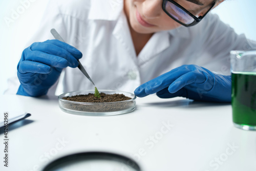 woman in white coat examines plants microbiology Professional