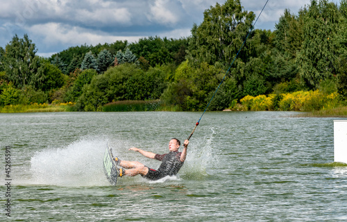 Summertine, watersports, activity and vacation concept. Outoor shot of unrecognizable male rider making extreme jump, showing heelside back roll trick photo