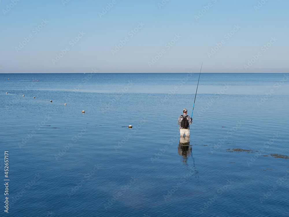 A fisherman catches a fish in the sea with a fishing rod. Active rest on the sea.