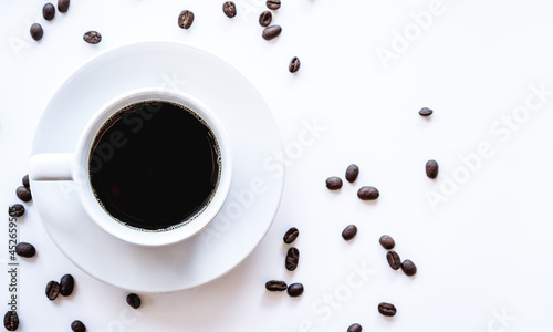 Flat lay of hot americano coffee in white coffee cup and coffee beans on white background with copy space