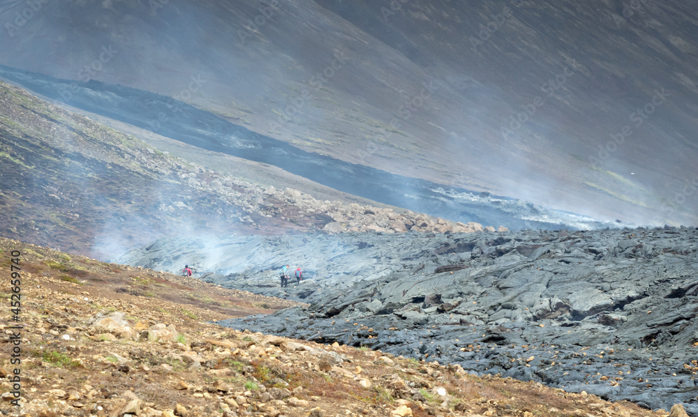 Grindavik, Iceland - July 26, 2021: A unique natural attraction. People are walking over the new lavafield of the volcano eruption at Fagradalsfjall Grindavik, Iceland - July 26, 2021: A unique natural attraction. People are walking over the new lavafield of the volcano eruption at Fagradalsfjall