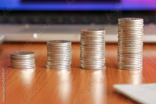 Stack of money coin with laptop computer open trading graph in the background, Business and Financial concept. 