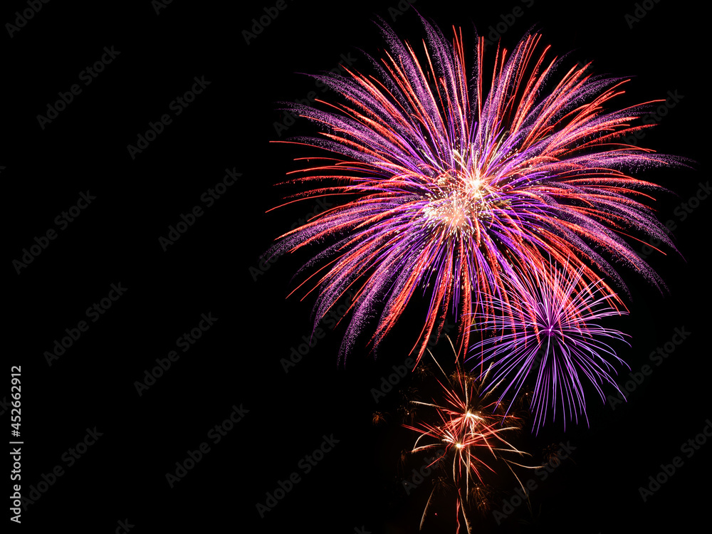 Large and colorful pink and purple display of fireworks in the night sky
