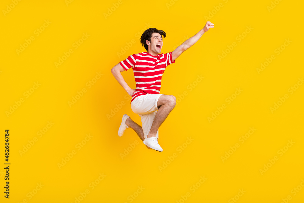Full size photo of happy joyful young raise hand super hero jump up empty space good mood isolated on yellow color background Full size photo of happy joyful young raise hand super hero jump up empty space good mood isolated on yellow color background