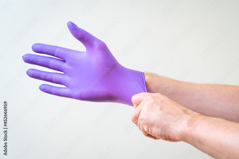 Male hand pulling a rubber glove on