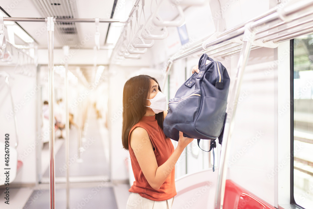 Asian tourist woman putting her luggage on overhead shelf in train Asian tourist woman putting her luggage on overhead shelf in train