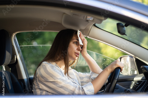Foto Girl driver being hot during heat wave in car, suffering from hot weather, has problem with a non-working air conditioner, wipes sweat from her face with tissue