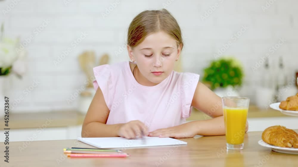 little girl draws while sitting in the kitchen
