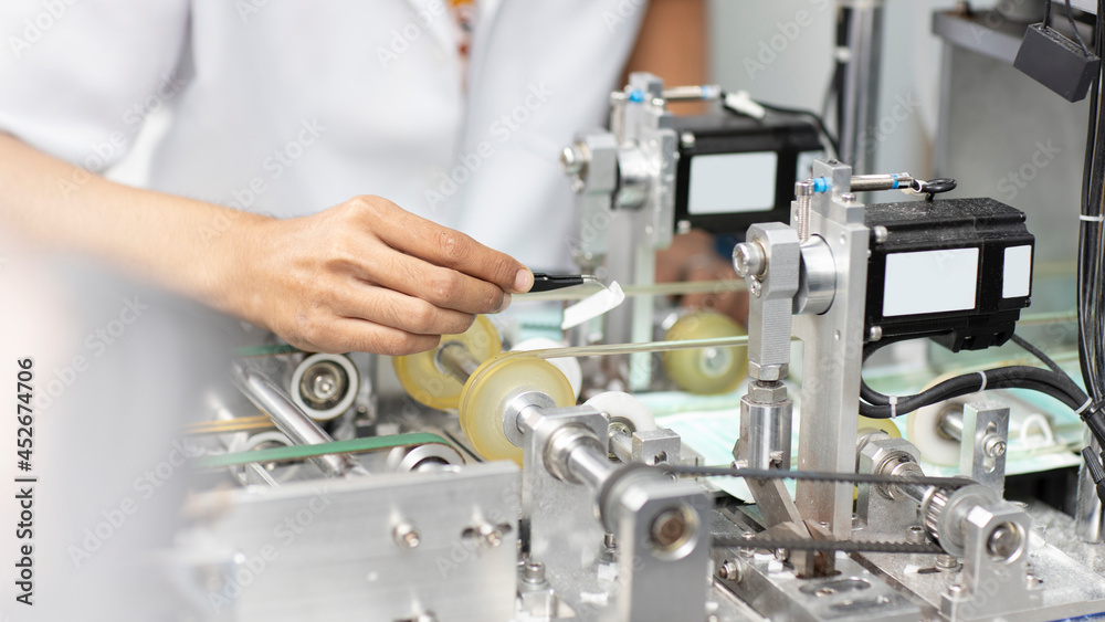 Asian worker hands inspecting quality of mask and medical face mask production line, Industry and factory concept. Asian worker hands inspecting quality of mask and medical face mask production line, Industry and factory concept.