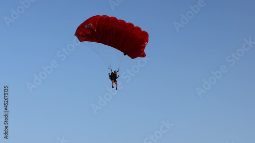 Parachute on the blue sky. Parachutist is flying slowly down with an open parachute. Skydiving, gliding, parachute jump