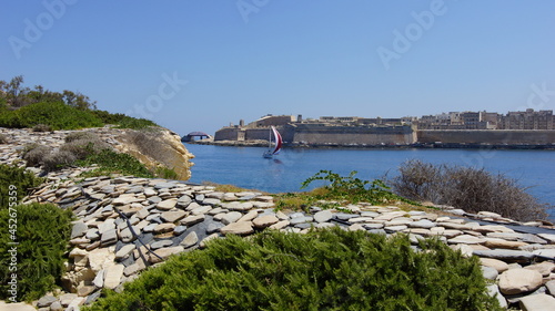 A sailboat sails along the Valletta Citadel. Malta.