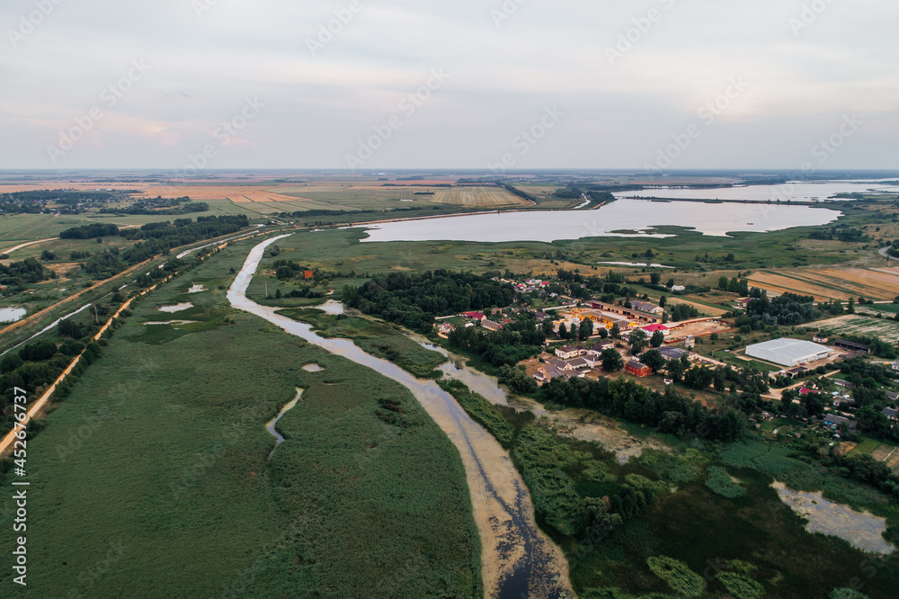 The river flows through the village and flows into the reservoir, shot from above