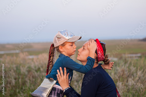 Mother and daughter hugging on nature landscape. Mom with child walking in the evening outdoor. Love, care, friendship,