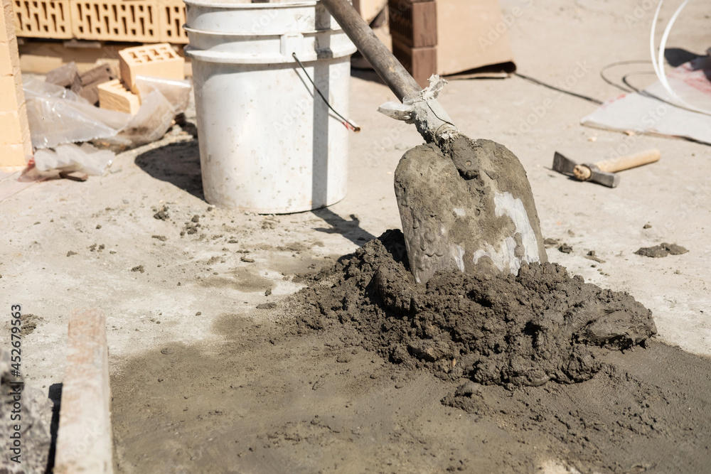 The builder poured cement mortar with rubble and concrete mortar, and spreads it with a shovel. Preparation for construction, laying the foundation of the house. The builder poured cement mortar with rubble and concrete mortar, and spreads it with a shovel. Preparation for construction, laying the foundation of the house.