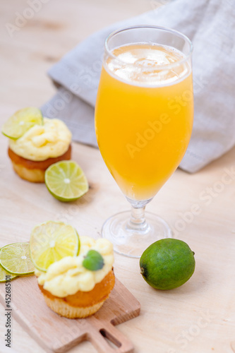 Glass of light beer with lime cupcake appetizer on light wooden background