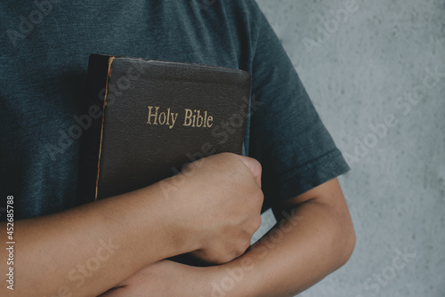 Women is holding and hug the bible in the morning. Hands folded in prayer on a Holy Bible in church concept. worship and religion. copy space