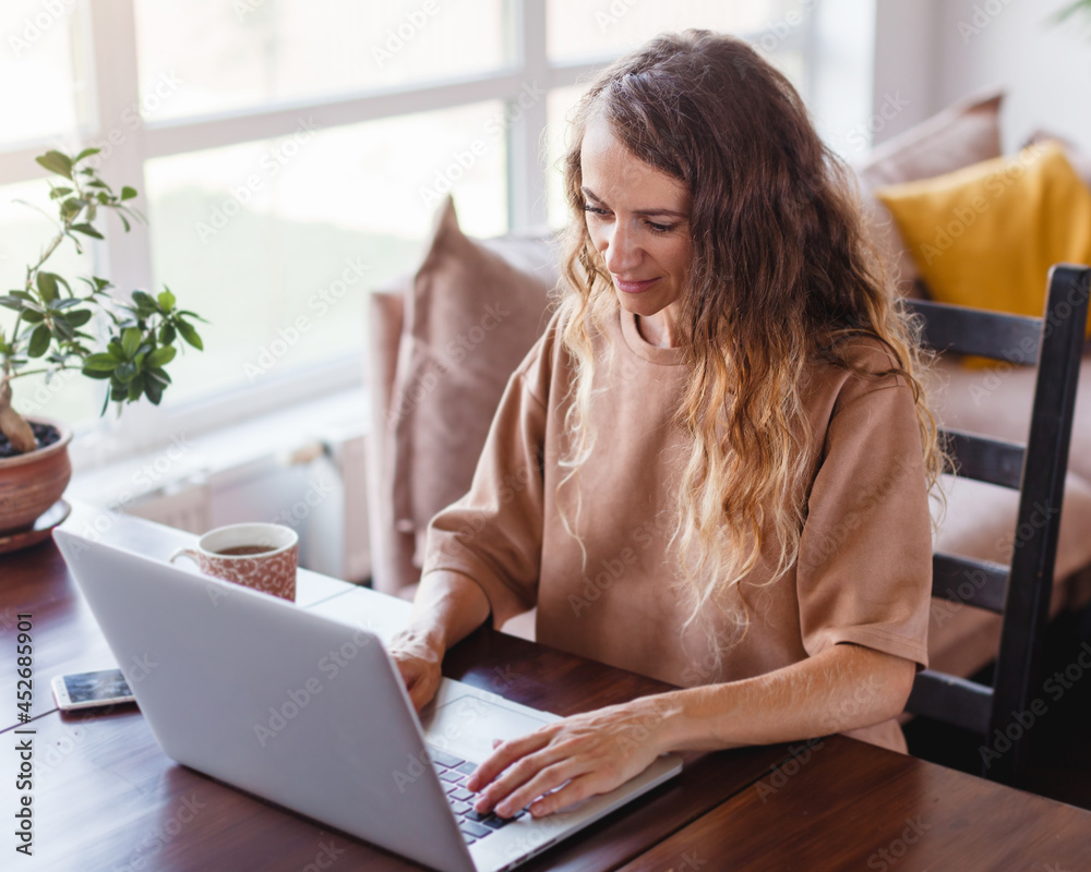Cheerful woman using silver laptop Cheerful woman using silver laptop