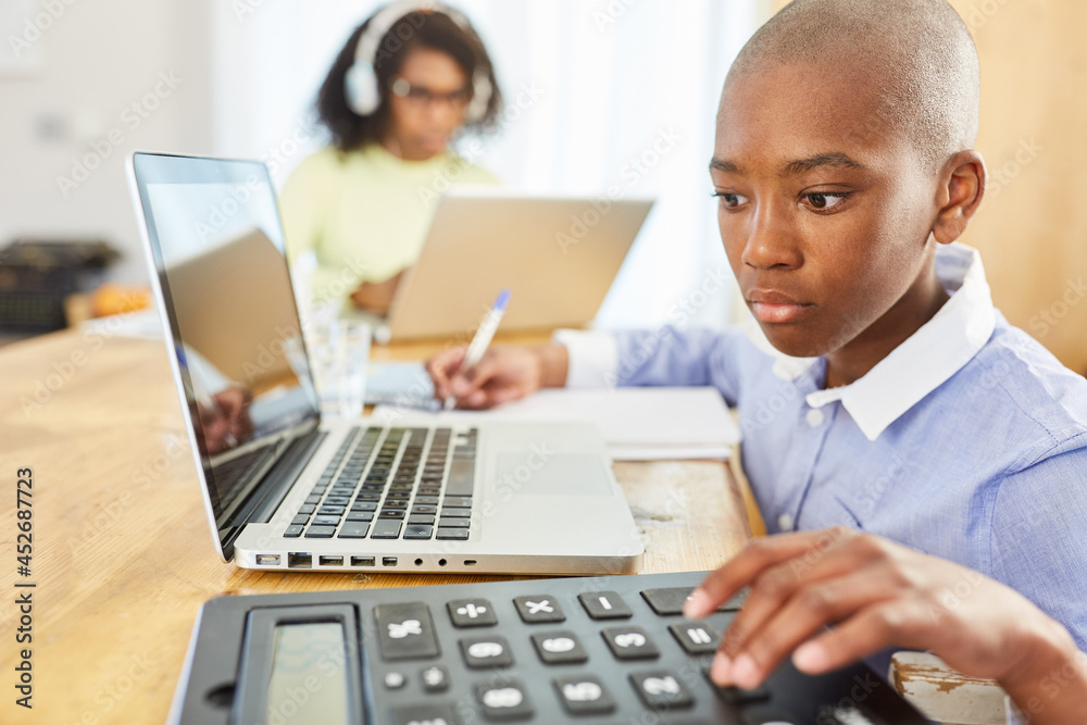 African boy at laptop computer while homeschooling