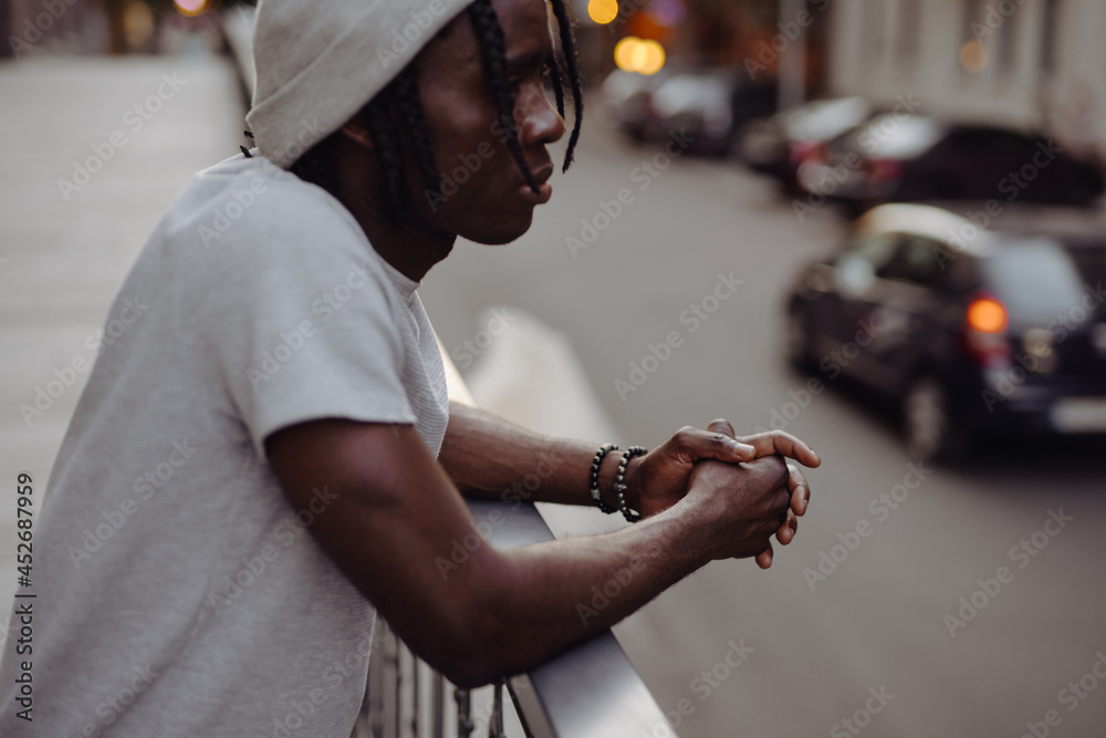 African American man leaning on terrace looks at cityscape
