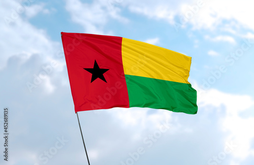 Flag of Guinea-Bissau, realistic 3d rendering in front of blue sky