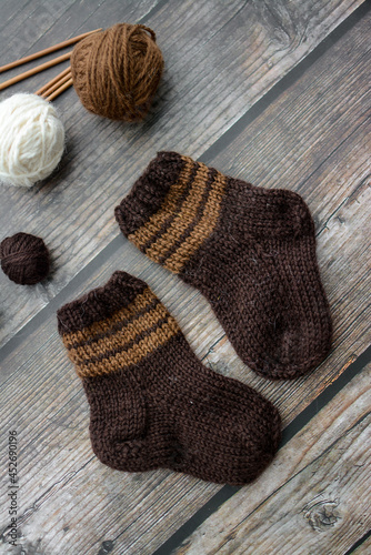 Small and warm newborn socks made of woolen yarn, on dark wooden background