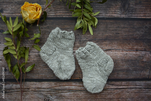 Small and warm newborn socks made of woolen yarn, on dark wooden background