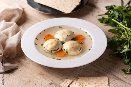 Traditional Jewish matzah ball soup on wooden table