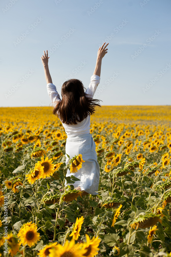 Young woman jumping happily in sunflower field Young woman jumping happily in sunflower field