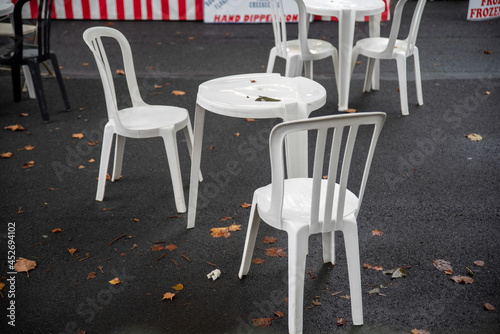Empty white lunch truck cafe tables and chairs set up in the street wet from rain