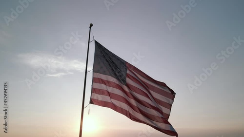 The American flag fluttering in the wind at sunset. A frame shot on the drone. High quality 4k footage
