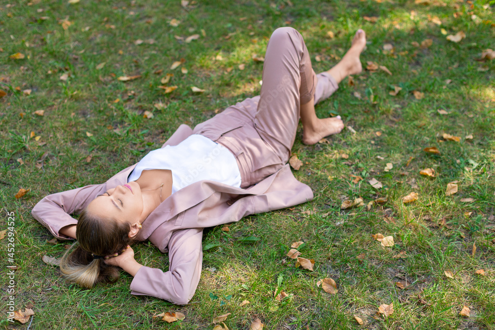 Pensive young woman lies in the park on the grass with closed eyes - digital detox concept. Pensive young woman lies in the park on the grass with closed eyes - digital detox concept.