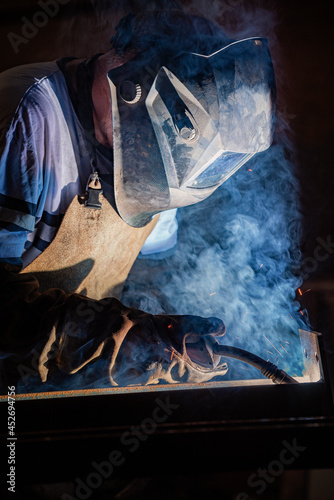 Welder works with a metal profile, iron construction production.