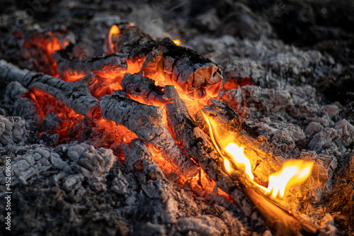 The bright fire of a campfire burning down in the night. Close-up. Soft focus