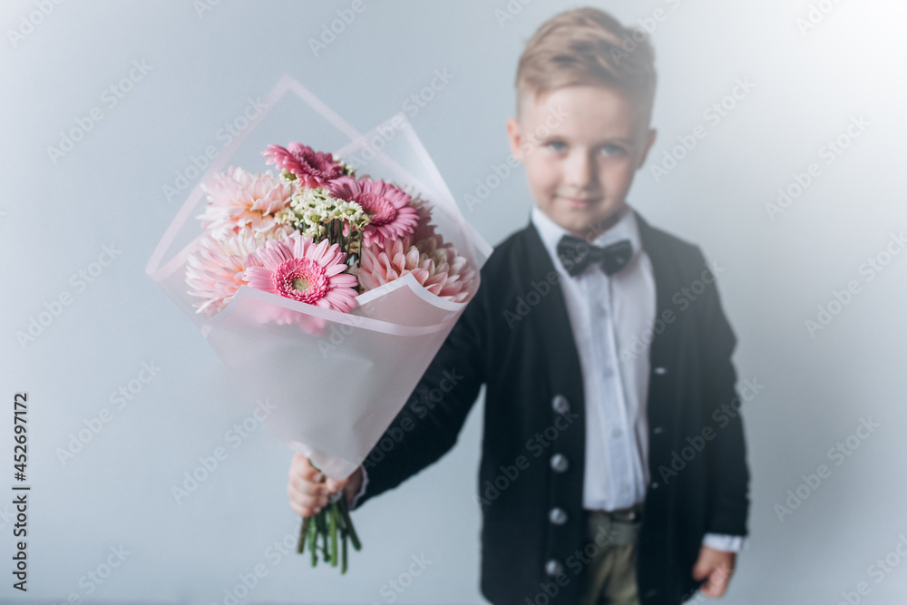 Cute adorable boy in suit with bouquet of fresh flowers. Little cheerful gentelman Cute adorable boy in suit with bouquet of fresh flowers. Little cheerful gentelman
