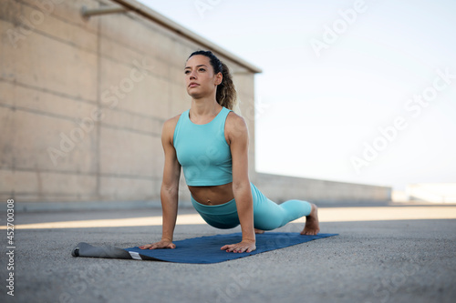 Young woman practising yoga outdoors. Beautiful girl stretching outside.