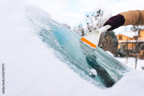 Person cleans the windshield of a car from ice with a scraper
