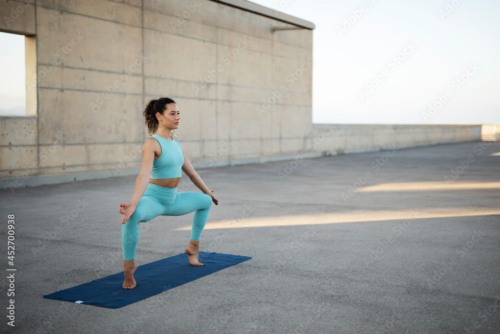 Young woman practising yoga outdoors. Beautiful girl stretching outside.