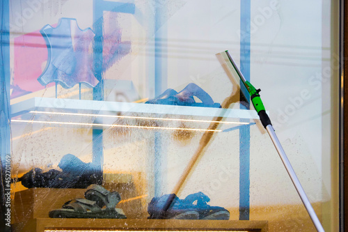 Washing shoe shop windows. Hand washing windows with special tools and tools. Cleaning storefront
