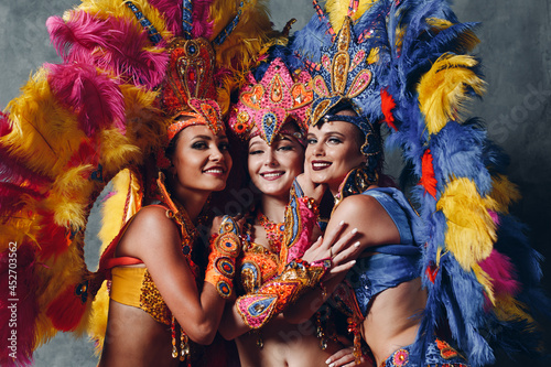 Photography Three Woman in brazilian samba carnival costume with colorful feathers plumage