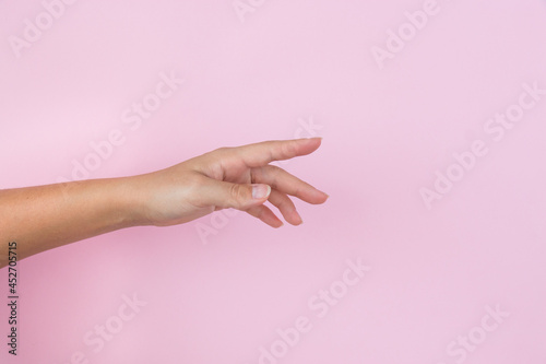 Elegant female hand with an empty palm down on a pink pastel background.