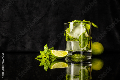 ingredients for a mojito cocktail in a glass and on black reflected surface photo